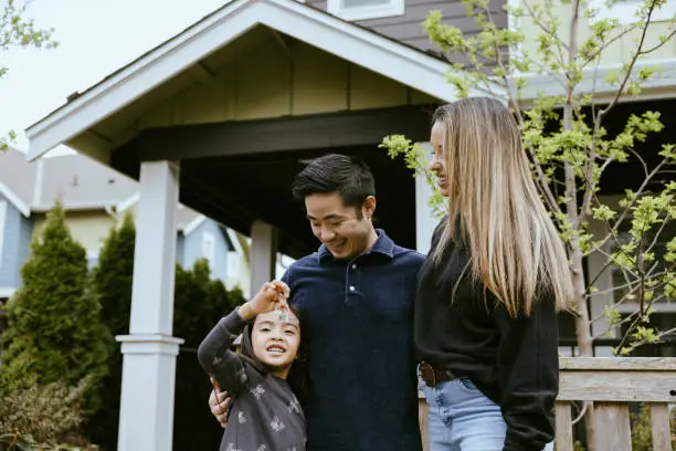 A family smiling in front of a newly purchased home